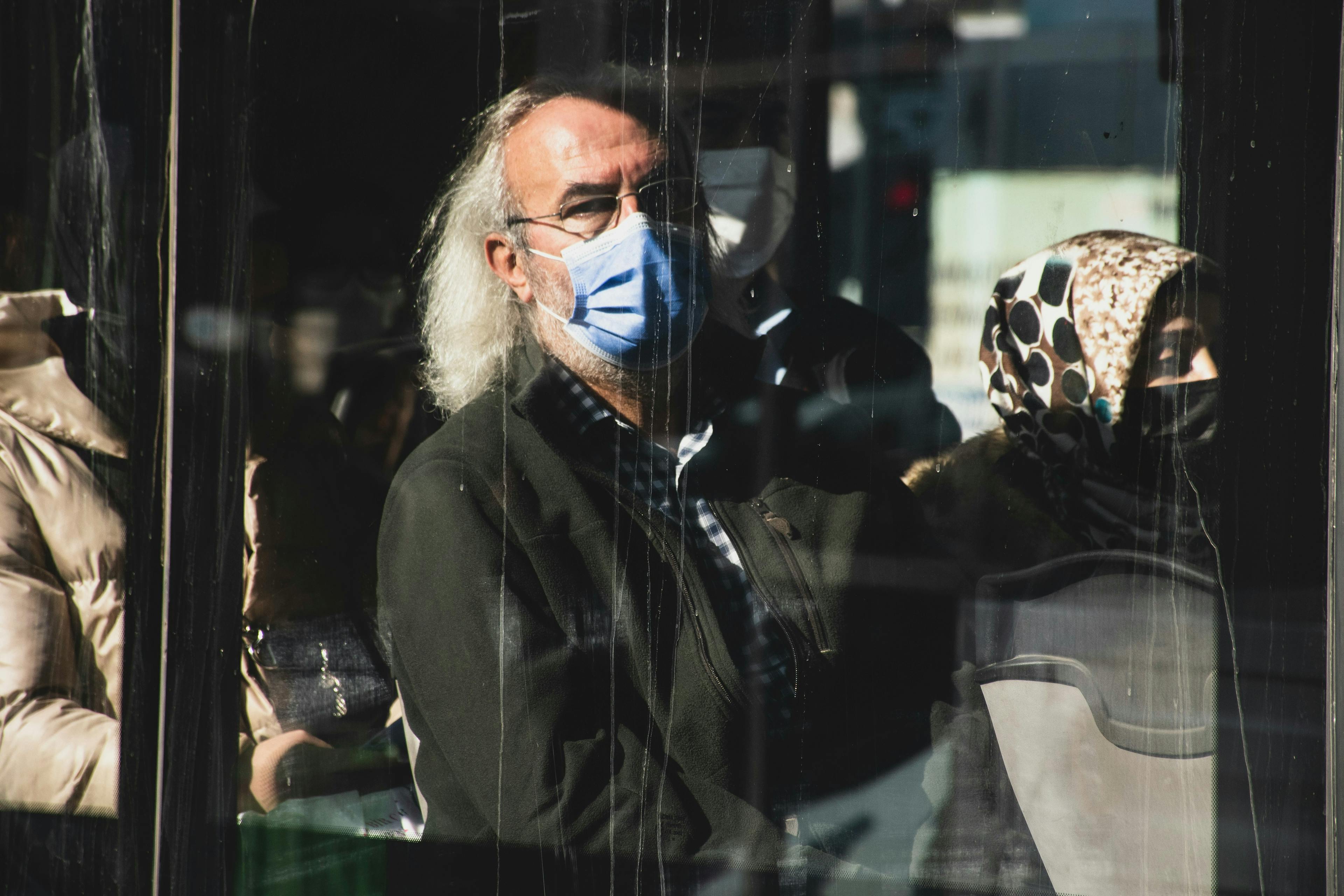 a man wearing a face mask looking out a window