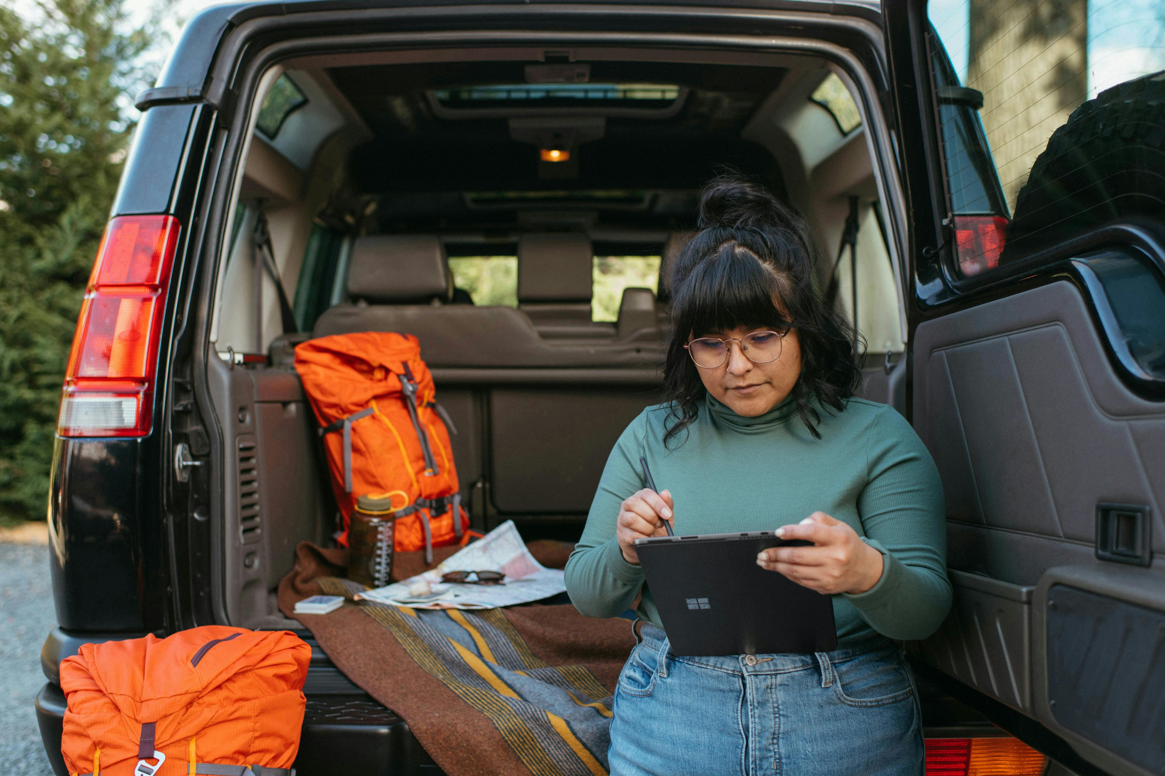 a woman standing in the back of a van holding a tablet