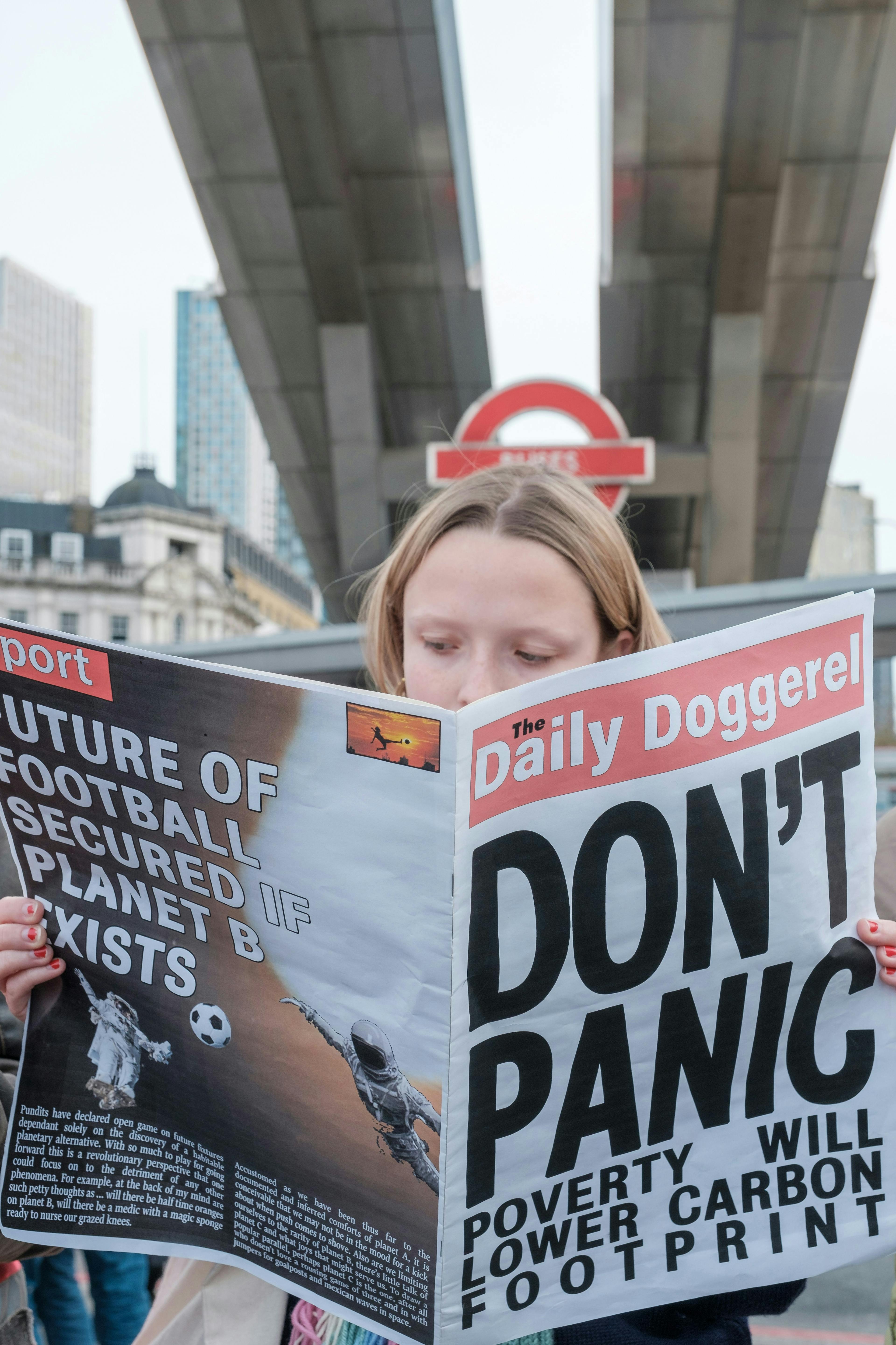a woman reading a newspaper with a bridge in the background