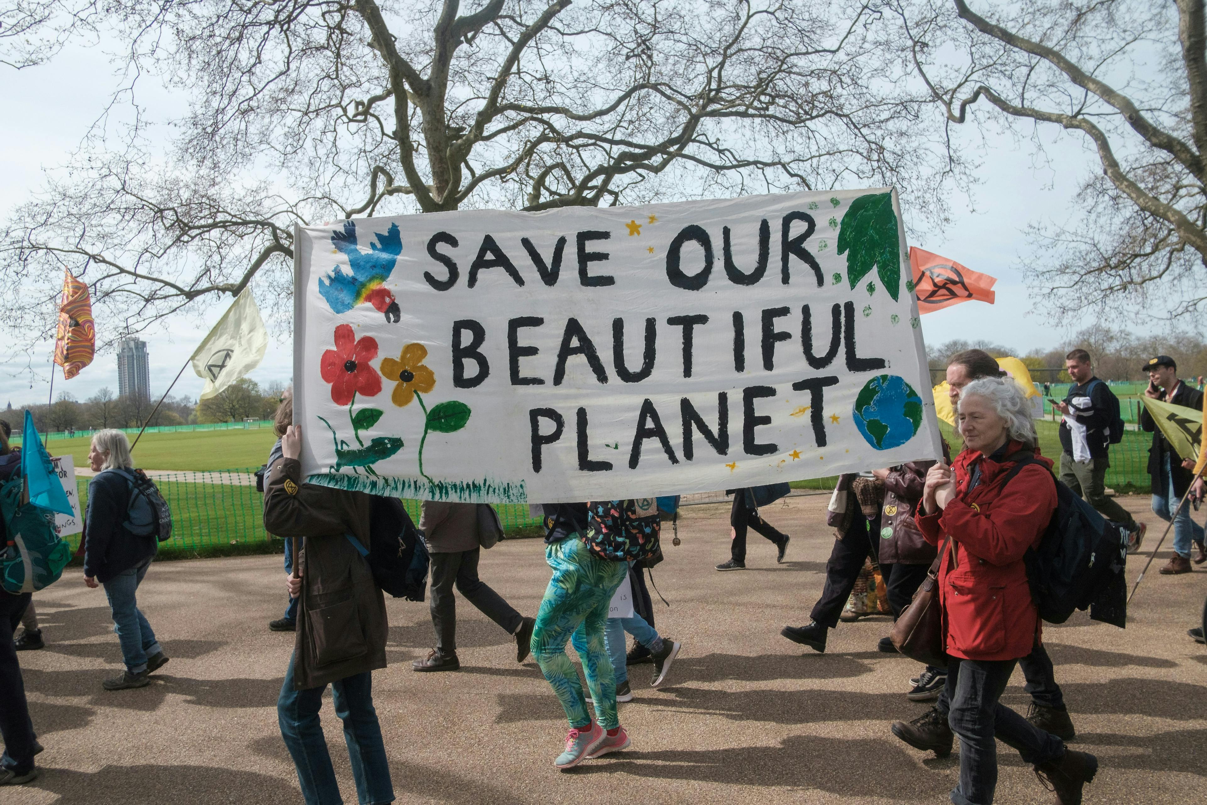 a group of people holding a sign that says save our beautiful planet